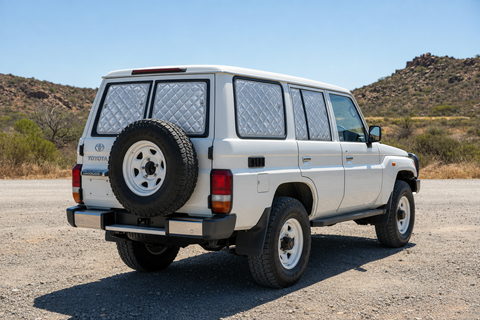 White LandCruiser 76 Series with silver quilted rear Touring screens, separate barn-door panes, fixed cargo window and clear front glass.
