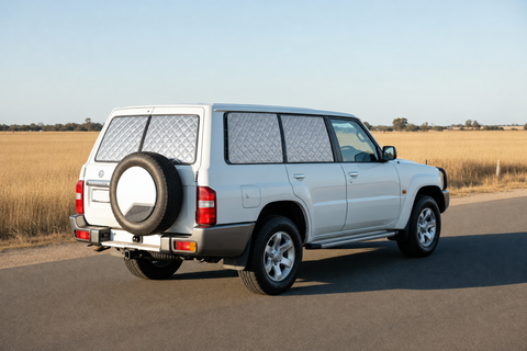 Nissan GU Patrol Touring Set with silver quilted insulated block-out screens on rear passenger, fixed cargo and both rear barn-door windows, with front windows clear.