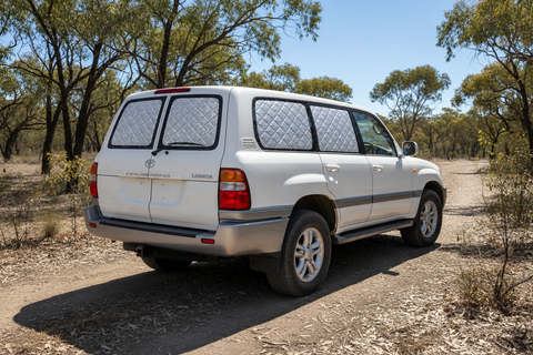 White Toyota Landcruiser 100/105 Series GX with silver insulated block-out screens on both rear barn-door windows and rear side windows.
