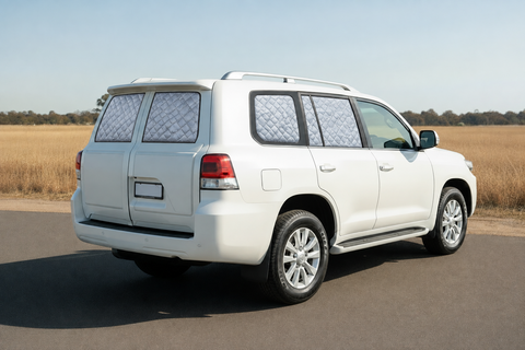 White Toyota Landcruiser 200 Series GX with silver insulated block-out screens on both rear barn-door windows and rear side windows, with front windows clear.